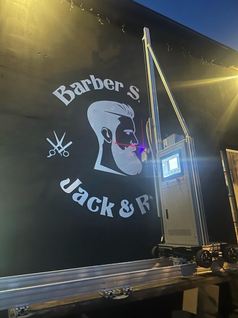 Direct UV wall print of a vintage barber shop logo on a dark background using a vertical wall printer.